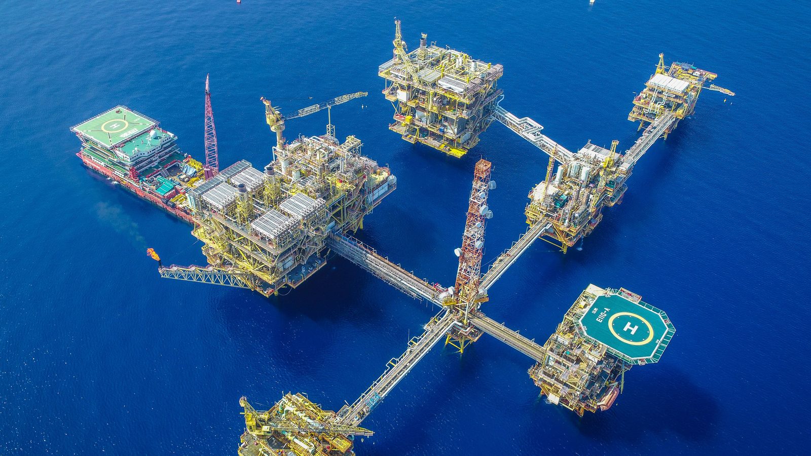 Aerial view of an offshore platform complex with bridge-linked platforms and two helidecks