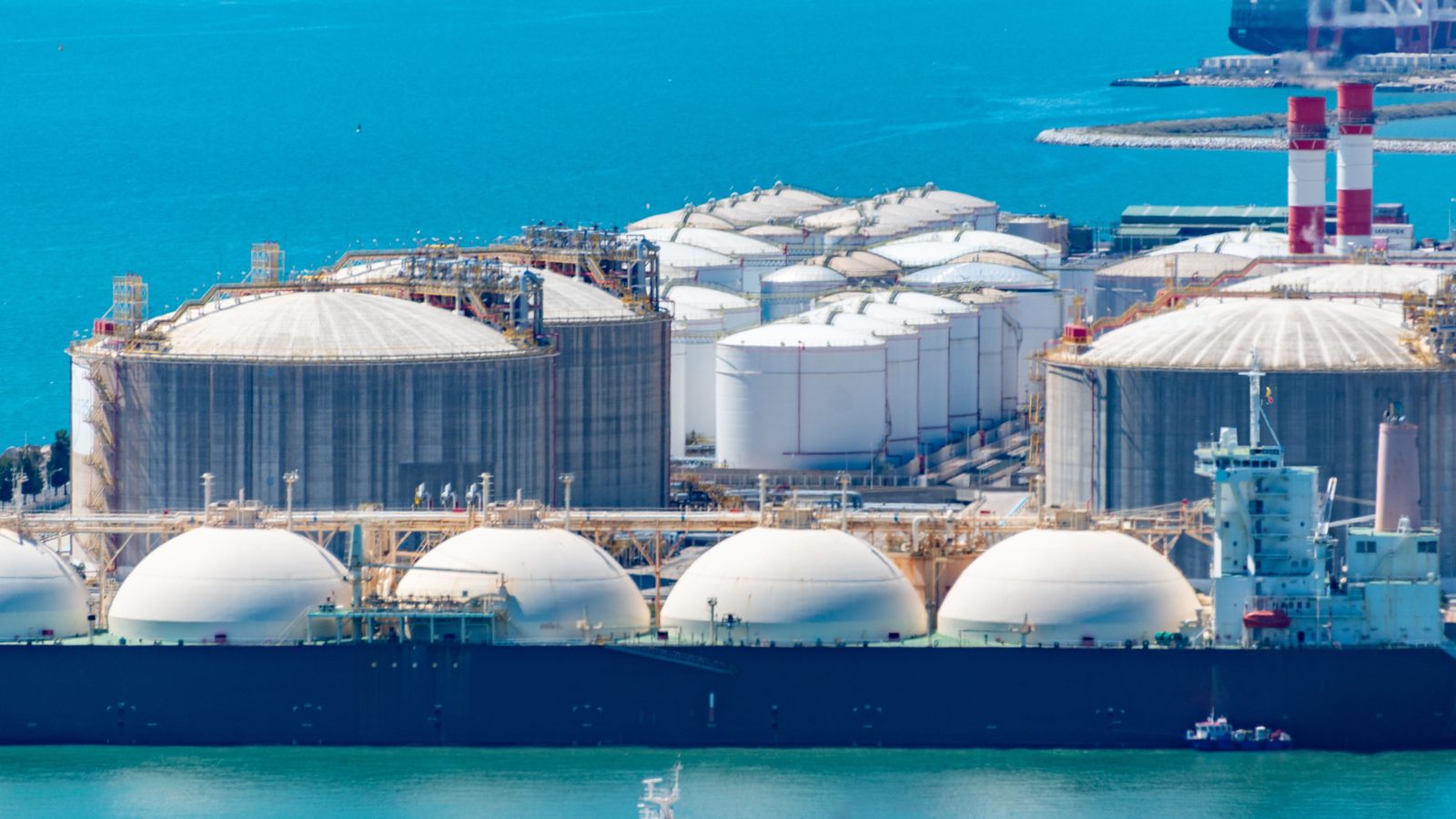 LNG carrier moored alongside an LNG terminal with storage tanks
